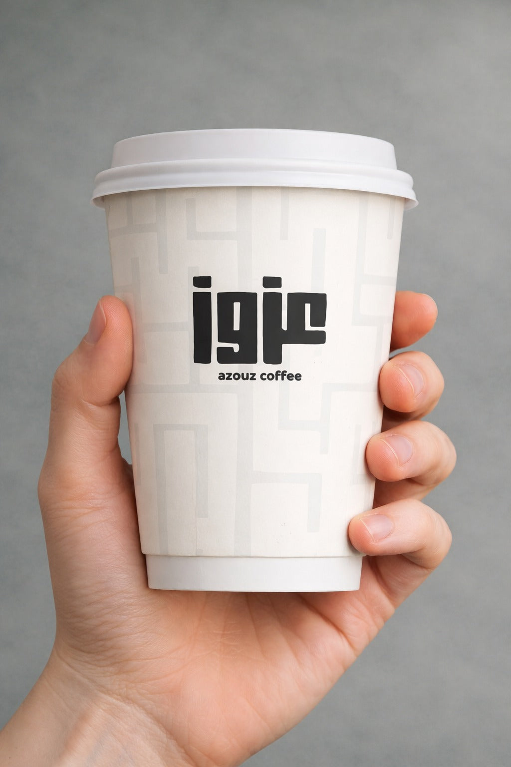 A hand holding an Azouz Coffee takeaway cup